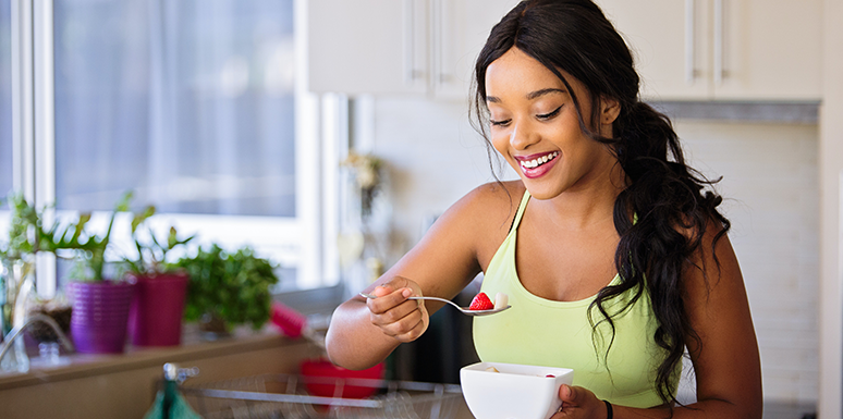 smiling woman eating bowl of fruit